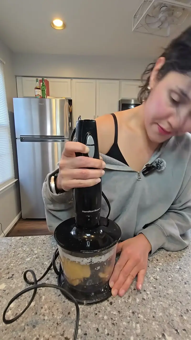 Crystal pulsing pumpkin puree and flour in a food processor on her kitchen counter