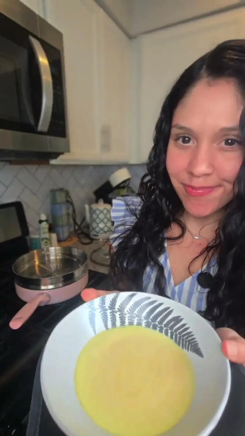 A bowl of pale yellow beaten egg held over the stove, ready to steam