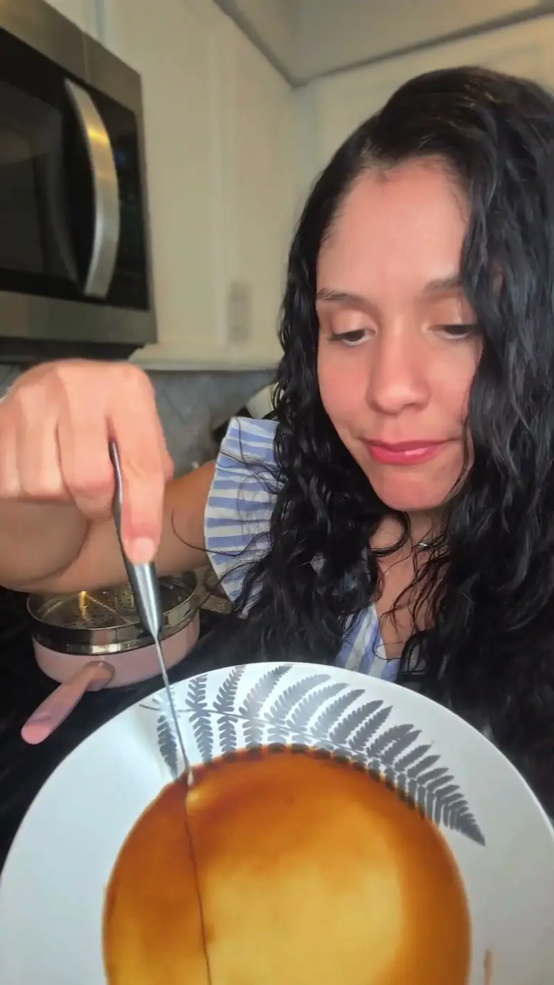 Crystal cutting into a bowl of glossy steamed egg custard with a knife