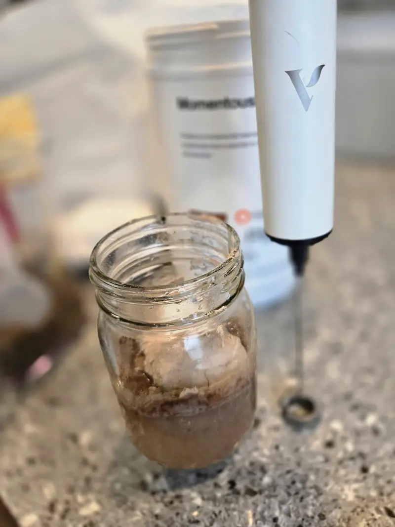 Frothing the protein powder and water together in the jar with a handheld frother