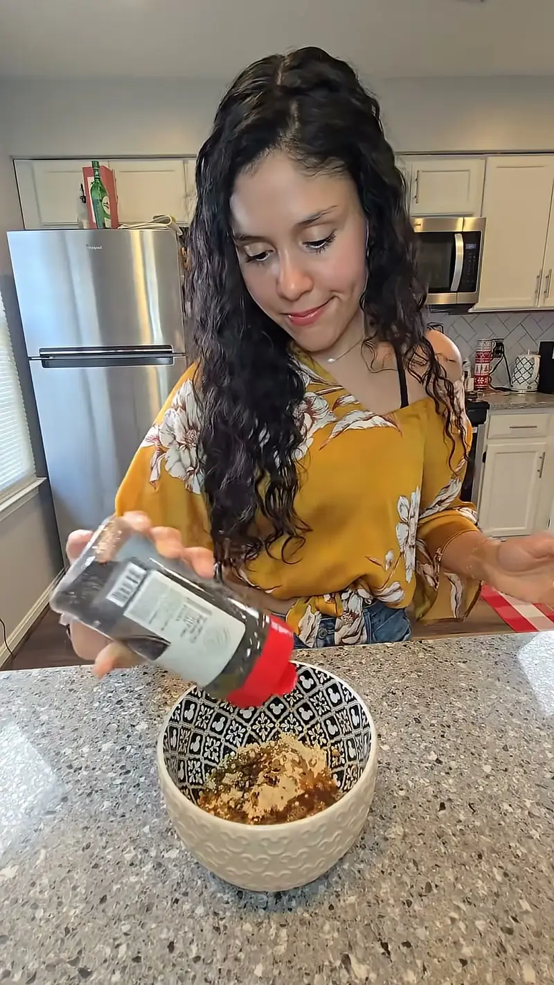 Crystal shaking seasoning into a patterned bowl of tofu