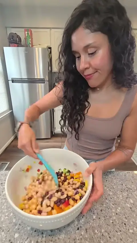 Crystal stirring the chopped peppers and beans together with a blue spatula