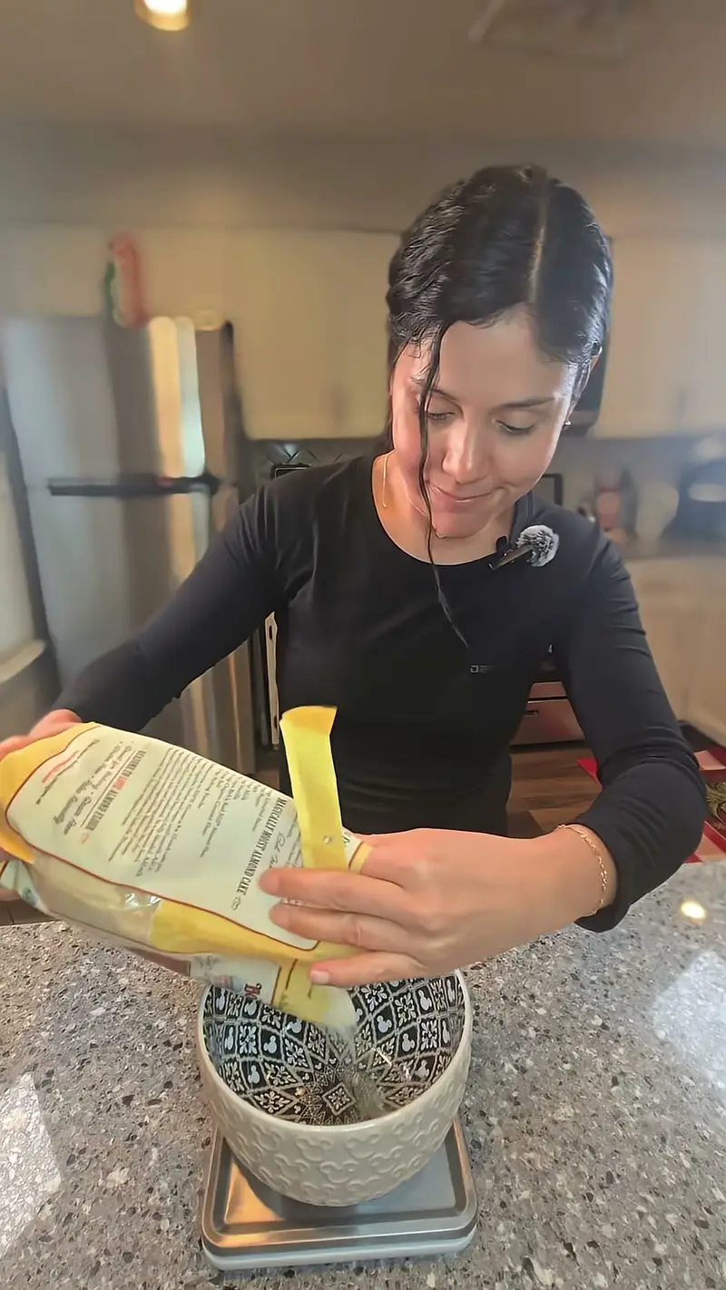 Crystal tipping flour from a bag into a bowl on the kitchen scale