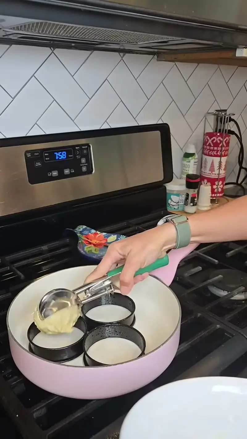Crystal spooning batter into metal rings set in a pink pan