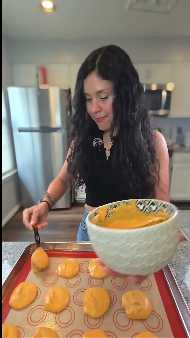 Crystal spooning the pumpkin cheesecake mixture onto a lined baking tray