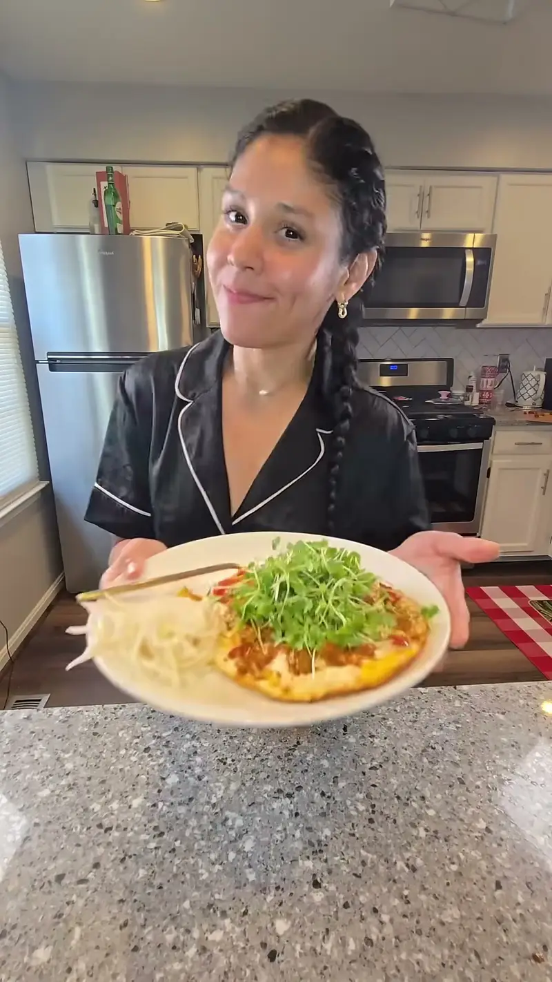 Crystal holding a plate of pan-cooked eggs with tomatoes and greens