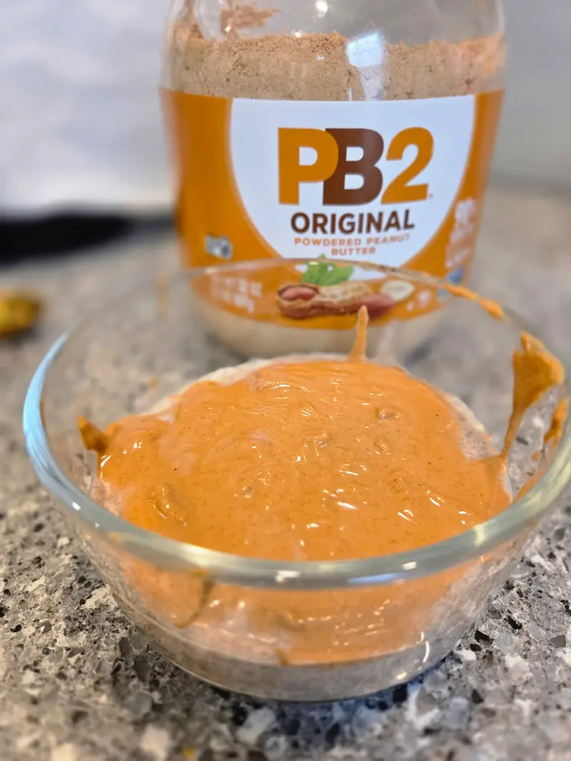 A bowl of peanut butter coconut chia pudding beside a jar of PB2 powder