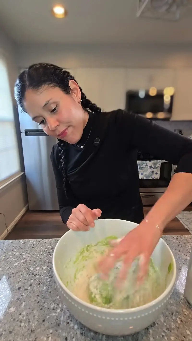 Crystal mixing the bright green spinach pasta dough by hand in a bowl