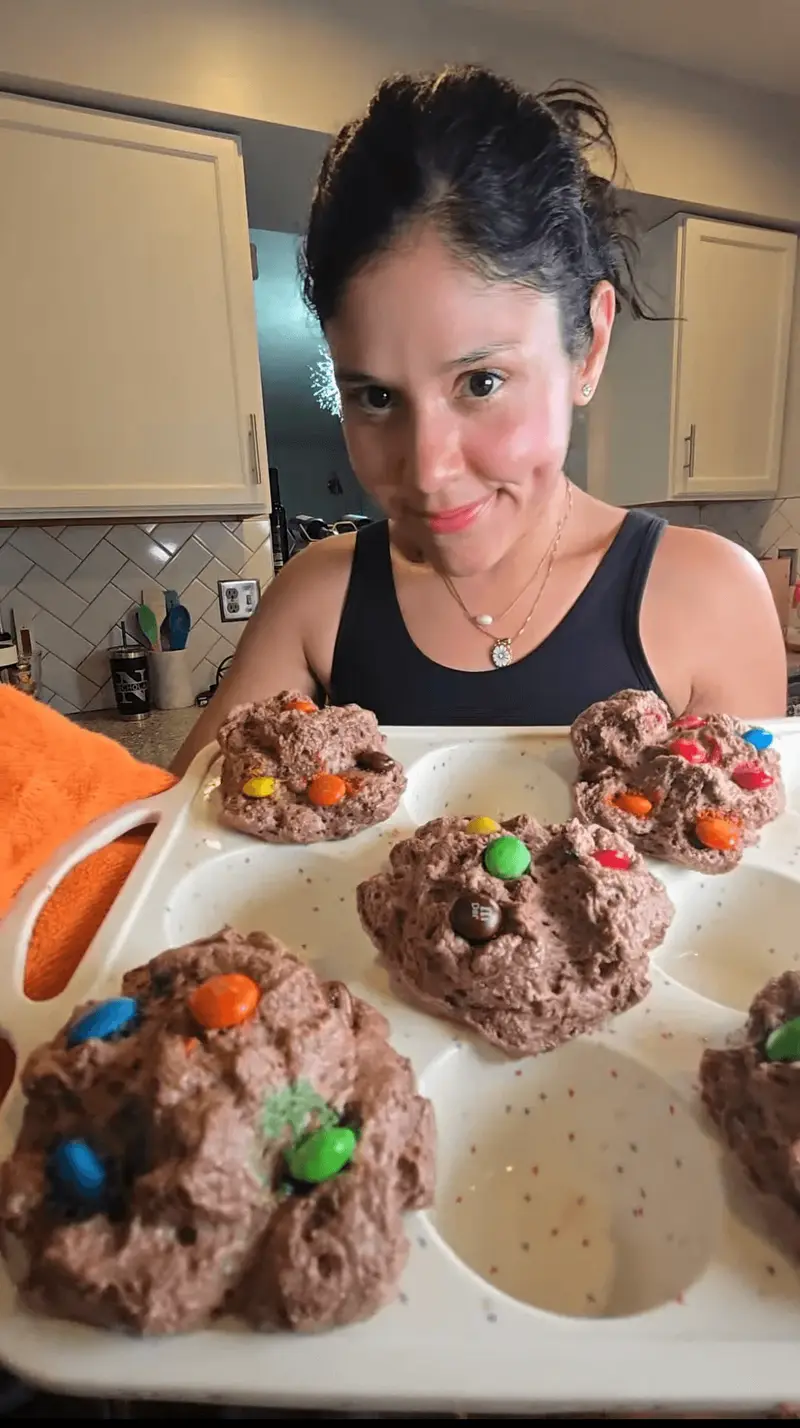 Crystal behind a tray of chocolate protein muffins topped with candy-coated chocolates